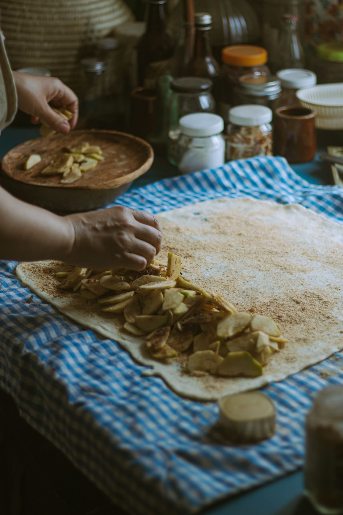 Sliced apples being laid by hand onto stretched strudel pastry before it is rolled